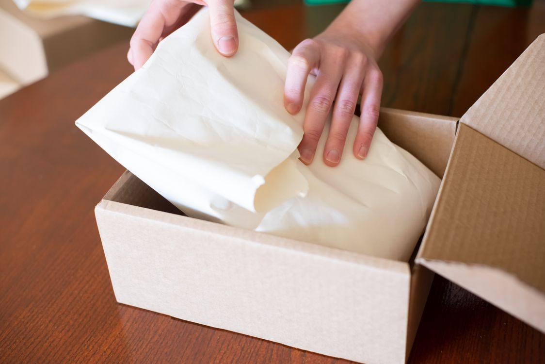 商品を包装紙で丁寧に包み、箱に収める手元